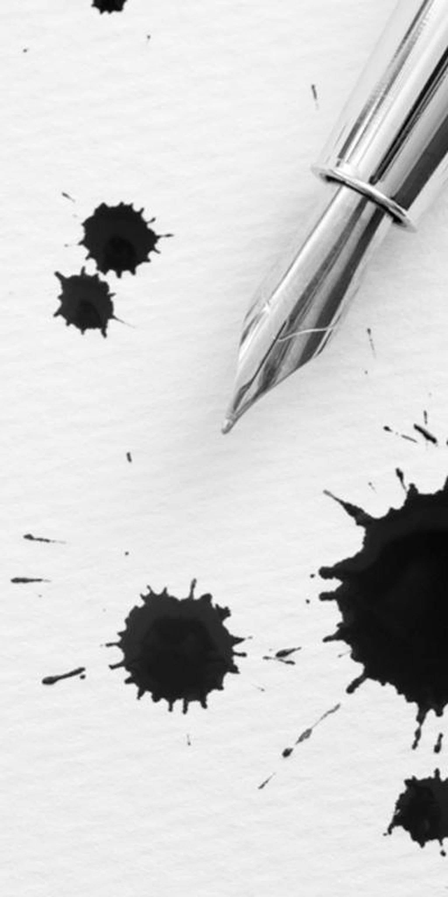 Pen with ink spots splattered on a page